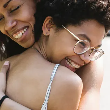 African American mother and teen daughter hugging