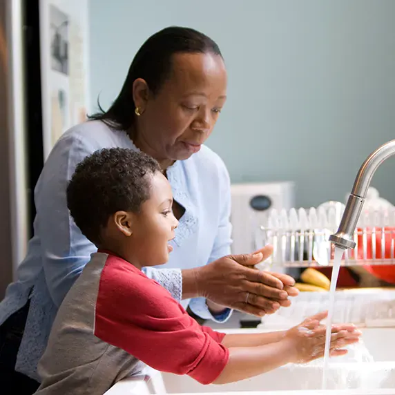 African American grand-mother and grand-son washing their hands at the kitchen